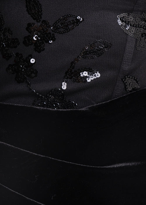 Close up swatch of black velvet mini dress embellished with black beads and sparkly sequins.