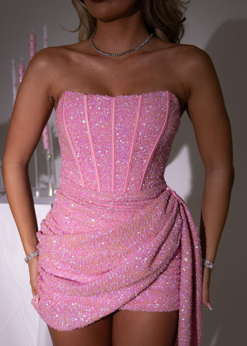Glamourous pink sequin strapless mini dress for women with corset-style bodice, draped waist, and elegant train - fitted bodycon party and event dress. Model: 5ft2, wearing size XS UK 6.