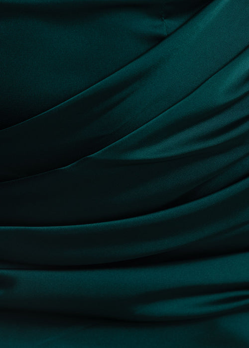 Women's emerald green satin mini dress with cowl neckline, ruching over the waist and floor length drape detail. Model is 5ft2' and wears a size XS 6.