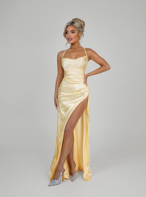 Women's pastel yellow satin prom gown with thigh slit and spaghetti style straps. Figure hugging fit. 