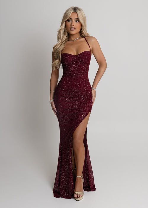 Women's burgundy maxi dress crafted with sparkle mesh fabric, thigh high slit and adjustable straps. Figure hugging fit and halter neckline.