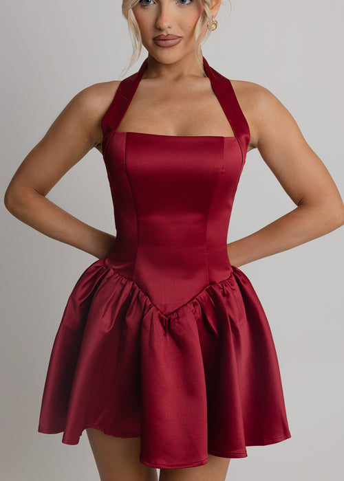 Women's wine halterneck skater style mini dress with drop waist and pleated skirt.