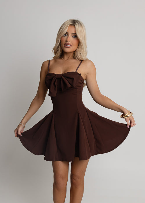 Women's brown dress with sweetheart neckline, oversized bow on bust and spaghetti straps. Brown mini dress is a floaty fit and mini length. Model is 5ft2' and wears a size XS 6.