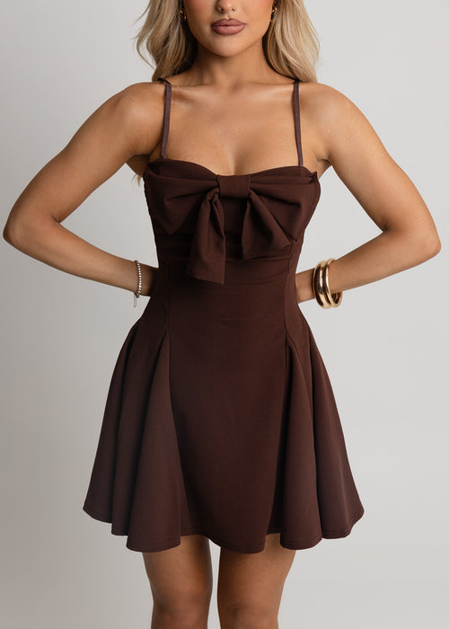 Women's brown dress with sweetheart neckline, oversized bow on bust and spaghetti straps. Brown mini dress is a floaty fit and mini length. Model is 5ft2' and wears a size XS 6.