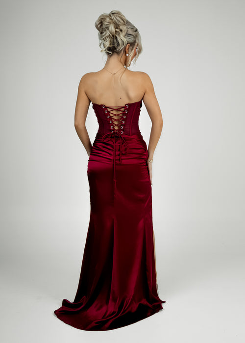 Women's wine satin corset style prom gown with satin and mesh corset bodice and wine satin skirt with thigh high slit and figure hugging fit.