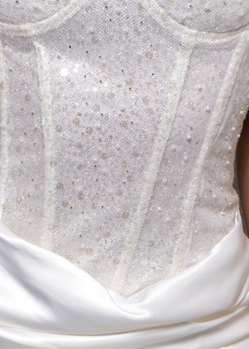 Close up white fabric embellished with sheer sequins and small pearls.