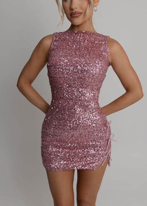 Women's pink sequin mini dress with racer style neckline and embellished pink and diamante bows. Model is 5ft2' and wears a size XS 6.
