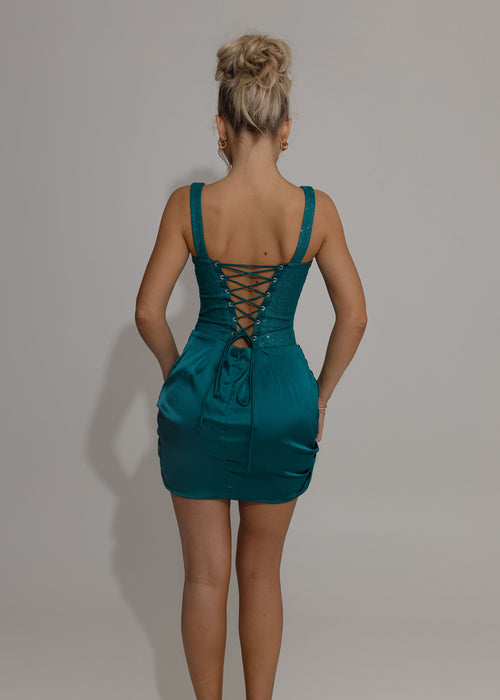 Women's teal mini dress. Corset bodice with teal glitter embellished fabric, corset boning for structured fit and a satin ruched mini skirt overlay. Model is 5ft2' and wears a size XS 6.
