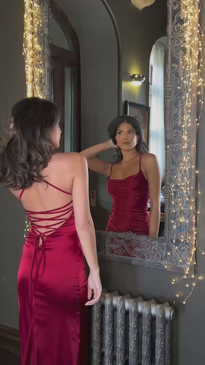 Women's red satin gown with thigh high slit, figure hugging fit and spaghetti straps. Model is 5ft6' and wears a size XS.